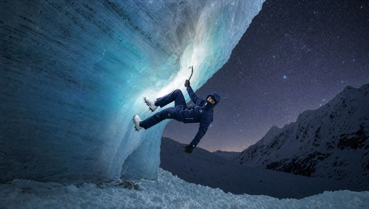 The navy CHASE HEAVEN Rain Shell worn while ice climbing beneath a starry night sky.